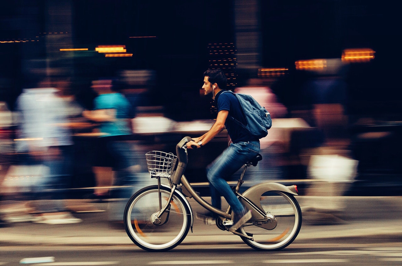 vyras važiuoja dviračiu gatvėje pro daug žmonių